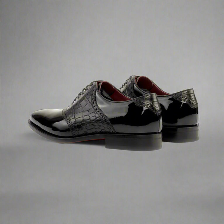 Black patent leather shoes with crocodile texture on a white background