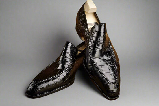 Pair of black crocodile-patterned loafers on a wooden surface