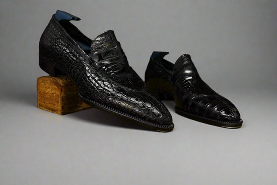 Pair of black leather shoes on a wooden surface with a brown background