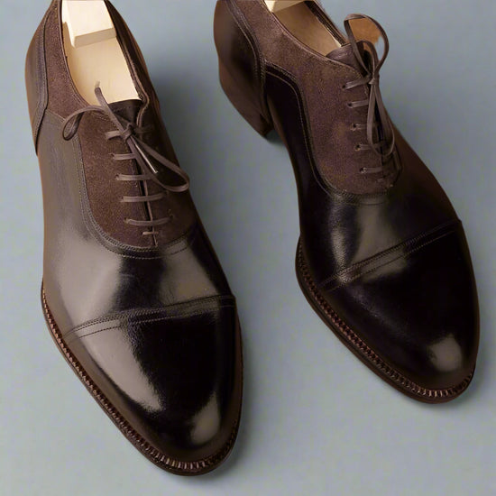 Pair of brown and black dress shoes on a textured surface