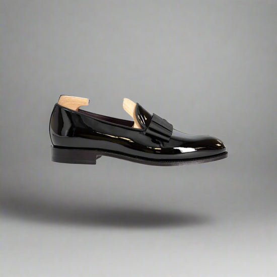 Black patent leather loafer with wooden sole on a white background