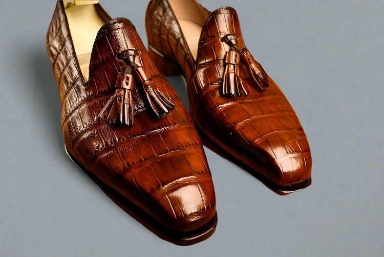 Brown leather loafers with tassels on a wooden surface
