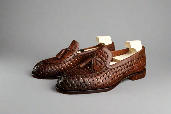Brown woven loafers on a wooden surface