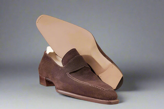 Brown suede loafer shoe on a textured fabric background