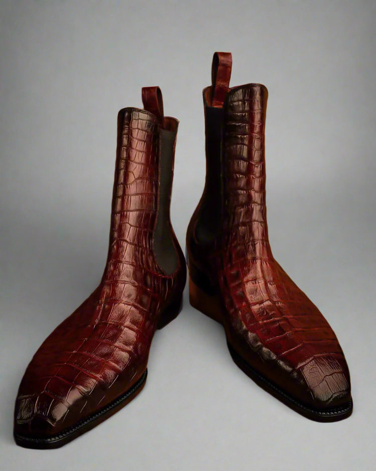 Pair of brown crocodile skin boots on a wooden surface
