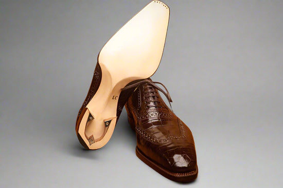 Brown leather shoe with white insole on a wooden surface