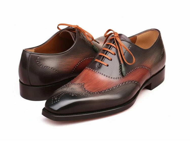 Pair of brown leather dress shoes with orange laces on a white background