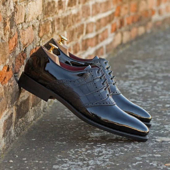 Blue dress shoes leaning against a brick wall.