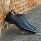 Blue dress shoes leaning against a brick wall.