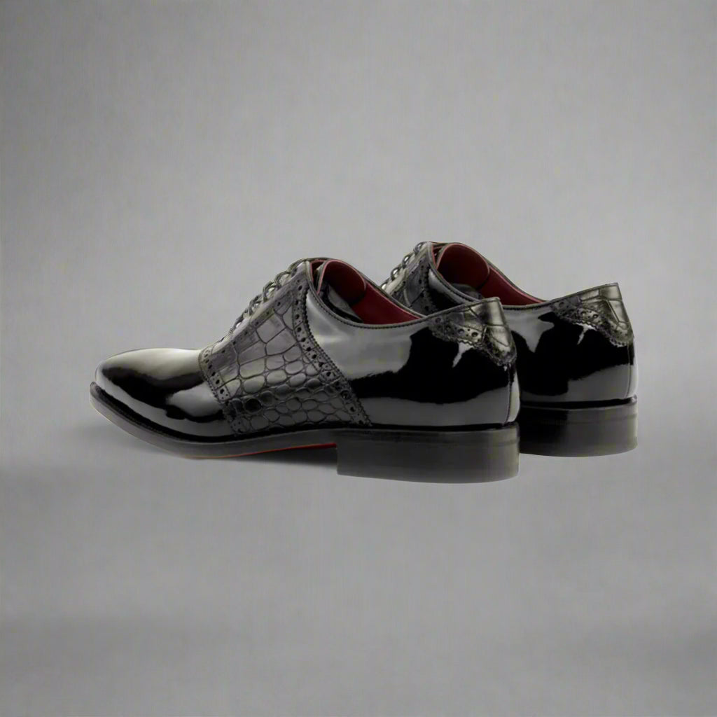 Black patent leather shoes with crocodile texture on a white background