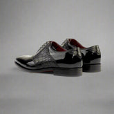 Black patent leather shoes with crocodile texture on a white background