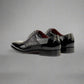 Black patent leather shoes with crocodile texture on a white background