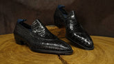 Black crocodile skin shoes on a wooden surface with a dark brown background