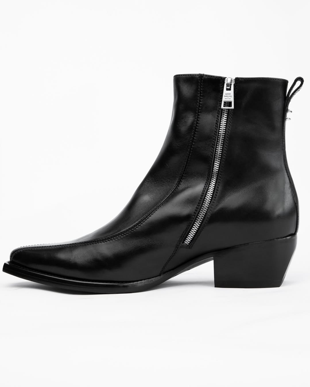 A black leather ankle boot with a side zipper, low block heel, and pull tab, shown from a side profile on a white background.