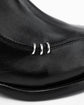 Close-up of a black leather boot featuring three polished silver metal decorative rings on the side, set against a plain white background.