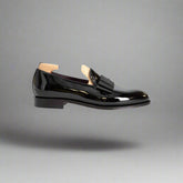 Black patent leather loafer with wooden sole on a white background