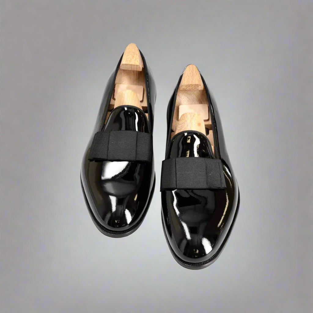 Pair of black patent leather shoes with wooden soles on a white background
