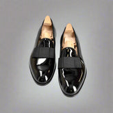 Pair of black patent leather shoes with wooden soles on a white background