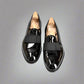 Pair of black patent leather shoes with wooden soles on a white background