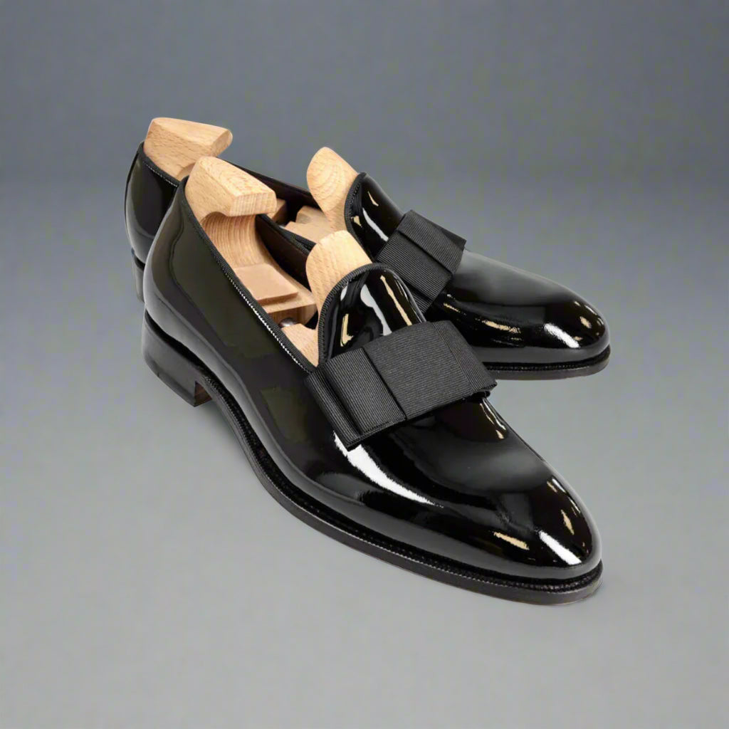 Black patent leather shoes with wooden insoles on a white background