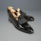 Black patent leather shoes with wooden insoles on a white background