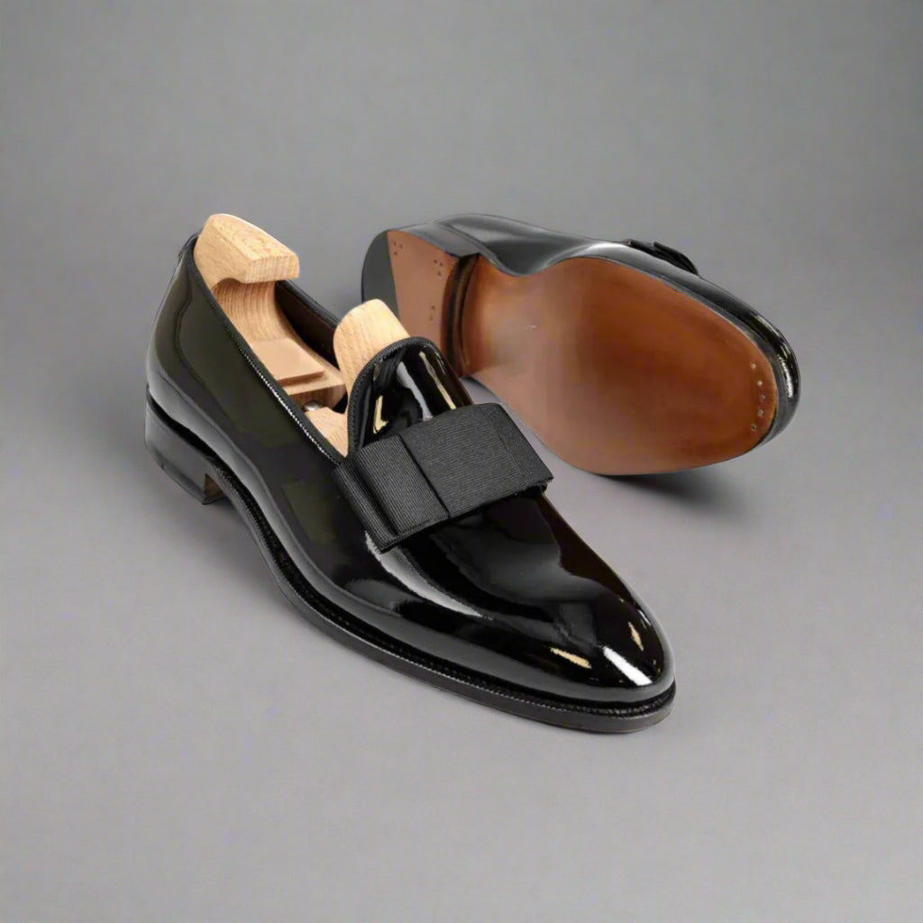 Black patent leather shoes with a wooden insole on a white background