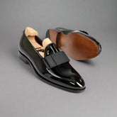 Black patent leather shoes with a wooden insole on a white background