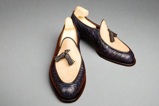 Pair of navy blue loafers with bow details on a wooden surface