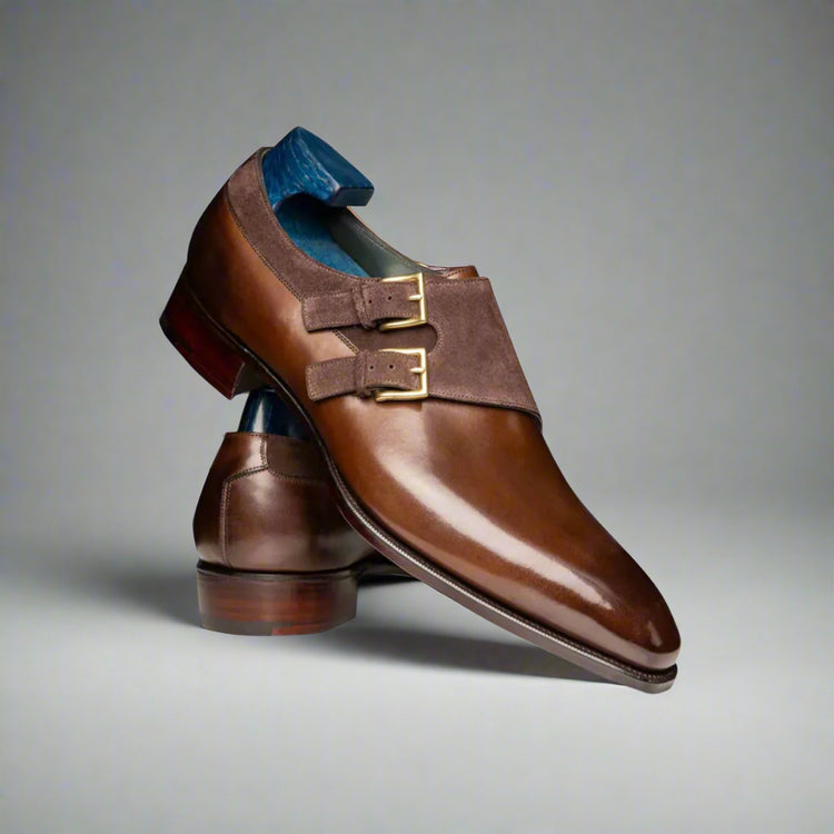 Brown leather shoes with gold buckles on a white background
