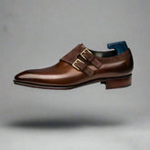 Brown leather dress shoe with gold buckle on a white background
