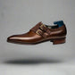 Brown leather dress shoe with gold buckle on a white background