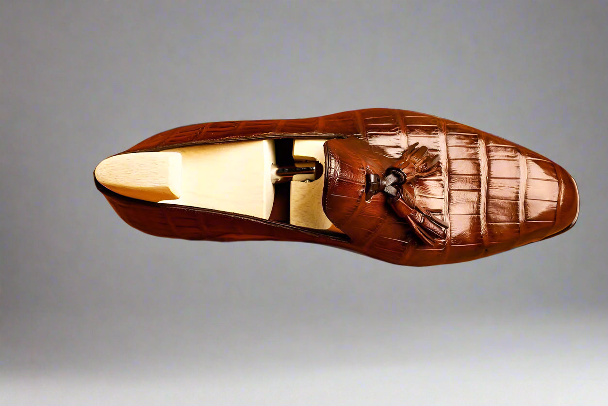 Brown leather loafer with a decorative bow on a wooden surface
