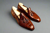 Pair of brown leather loafers with tassels on a wooden surface