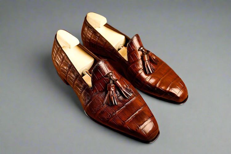 Pair of brown leather loafers with tassels on a wooden surface