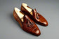 Pair of brown leather loafers with tassels on a wooden surface