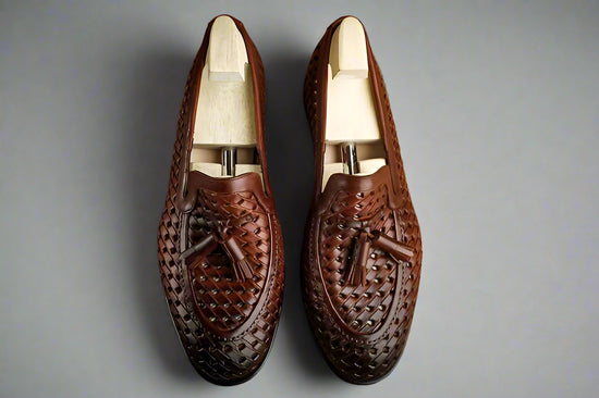 Pair of brown leather loafers with tassels on a wooden surface