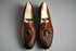 Pair of brown leather loafers with tassels on a wooden surface