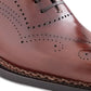 Close-up of a brown leather shoe with perforated design on a white background