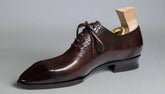 Brown leather dress shoe on a white surface with a blurred background