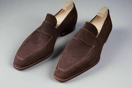 Pair of brown suede loafers on a textured surface