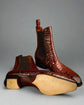 Brown crocodile skin boots on a wooden surface