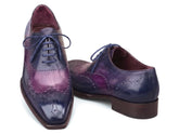 A pair of men's wingtip oxford shoes with a glossy purple and navy blue gradient finish, featuring dark brown soles and matching blue laces, shown against a plain white background.