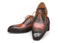 Pair of brown and black dress shoes with orange laces on a white background