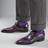 Purple dress shoes with gray trousers and purple socks on a white background