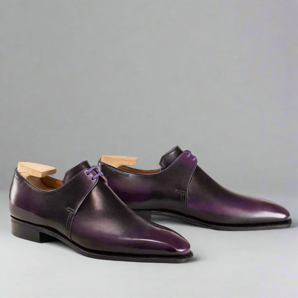 Pair of purple dress shoes with wooden soles on a white background
