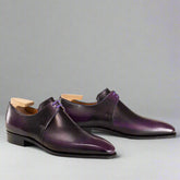 Pair of purple dress shoes with wooden soles on a white background
