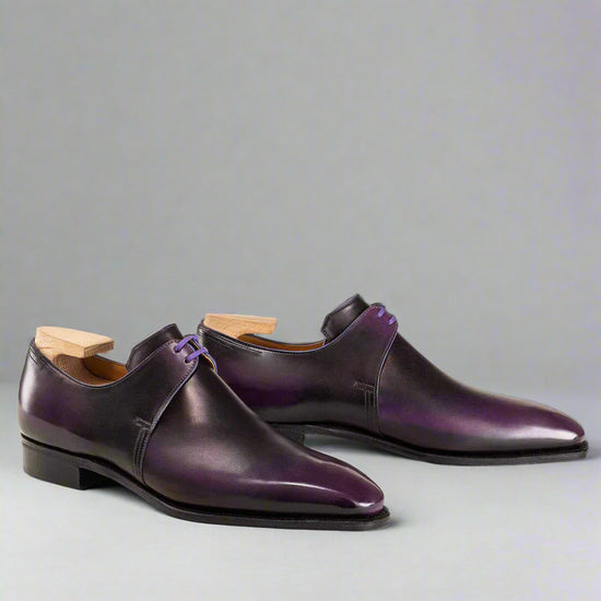 Pair of purple dress shoes with wooden soles on a white background