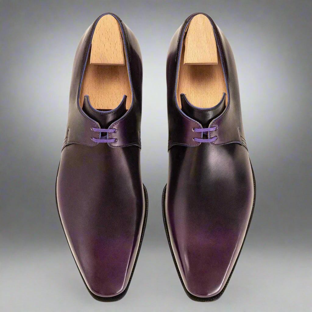 Pair of purple dress shoes with wooden soles on a white background