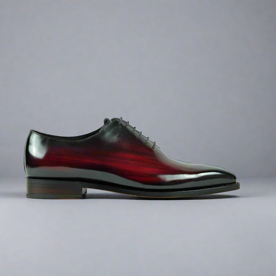 Shiny black and red leather shoe on a white background