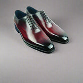 Pair of polished dress shoes on a blue box with a white background